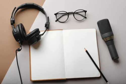 Koptelefoon, microfoon en open notitieblok met potlood op een minimalistisch bureau, podcastconcept of shownotities voor het maken van inhoud